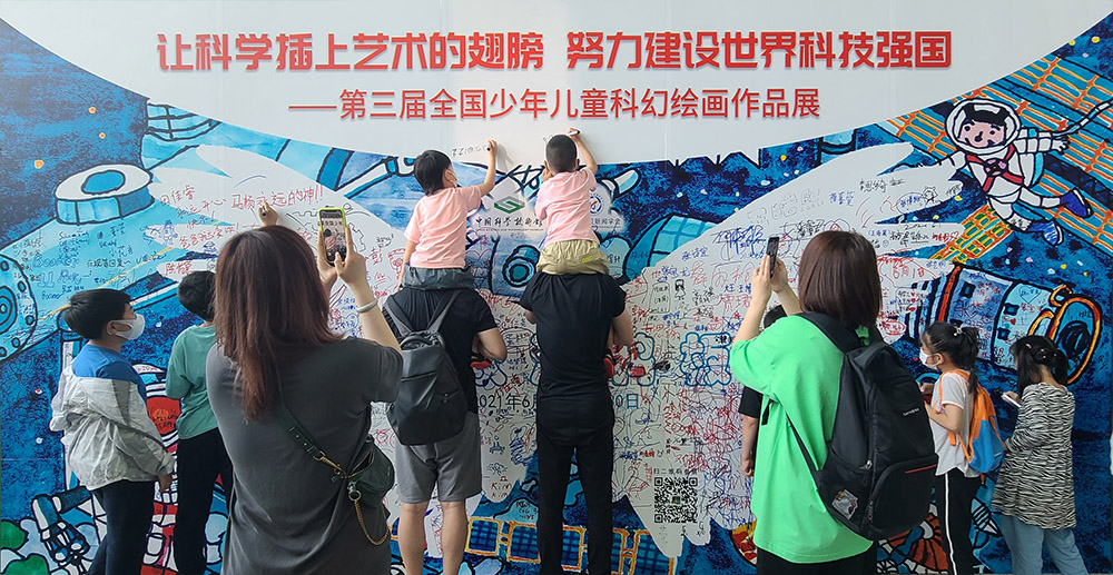 中国科技馆展厅大签名版前小作者骑在家长的肩膀上签名留念